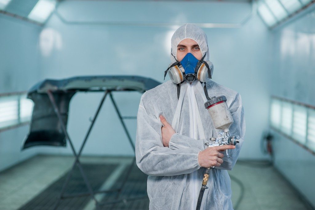 Man in protective gear holding a spray paint